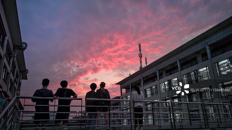 校园夏季晚霞火烧云与看晚霞的学生图片素材
