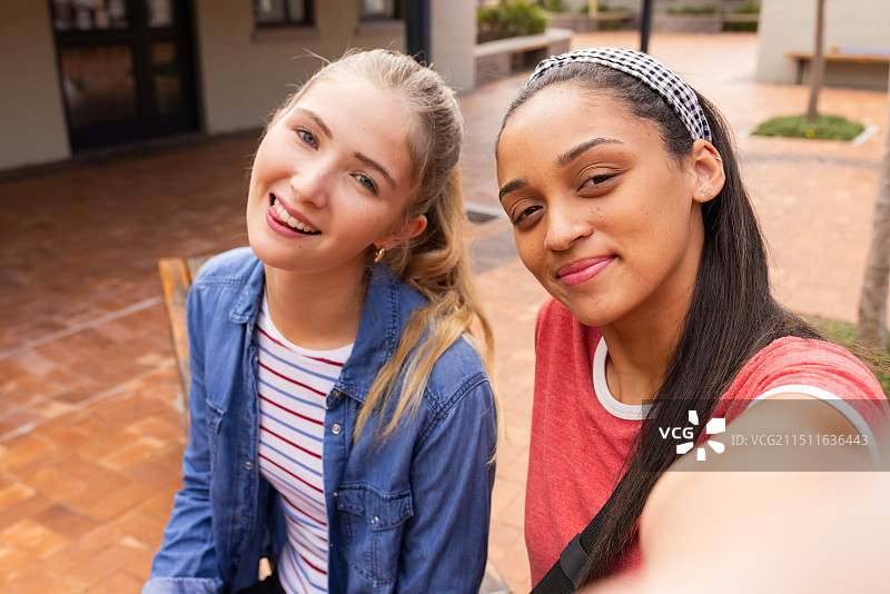 高中庭院里一起微笑自拍的少女图片素材