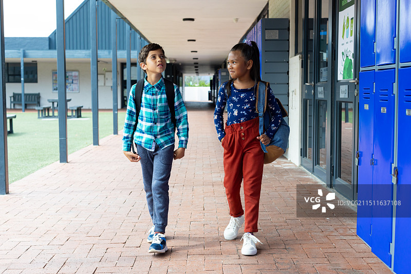 混血男孩和女孩走过学校的储物柜图片素材