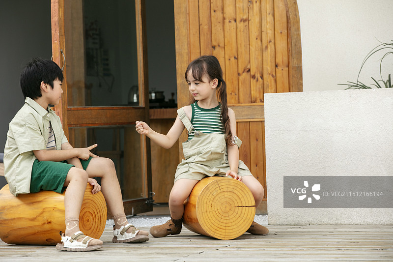 坐在度假屋前玩耍的两个小朋友图片素材