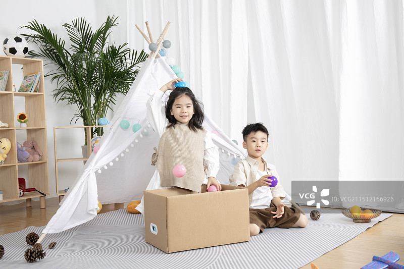 在儿童帐篷前玩纸箱子游戏的两个小朋友图片素材