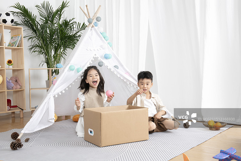 在儿童帐篷前玩纸箱子游戏的两个小朋友图片素材