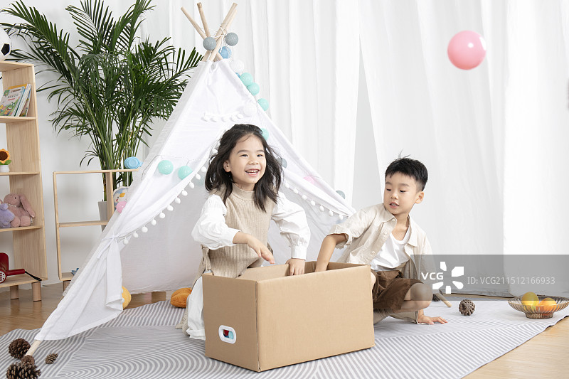 在儿童帐篷前玩纸箱子游戏的两个小朋友图片素材