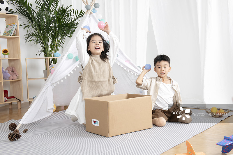 在儿童帐篷前玩纸箱子游戏的两个小朋友图片素材