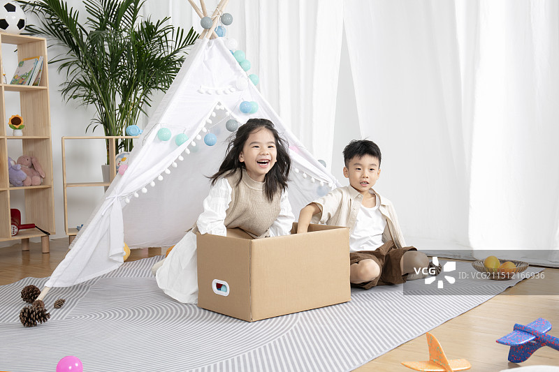 在儿童帐篷前玩纸箱子游戏的两个小朋友图片素材