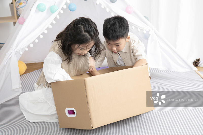 在儿童帐篷前玩纸箱子游戏的两个小朋友图片素材