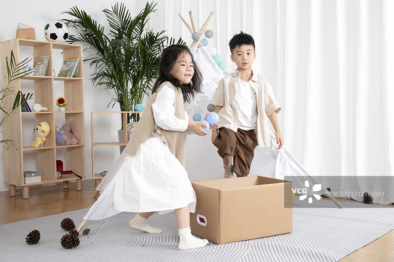 在儿童帐篷前玩纸箱子游戏的两个小朋友图片素材