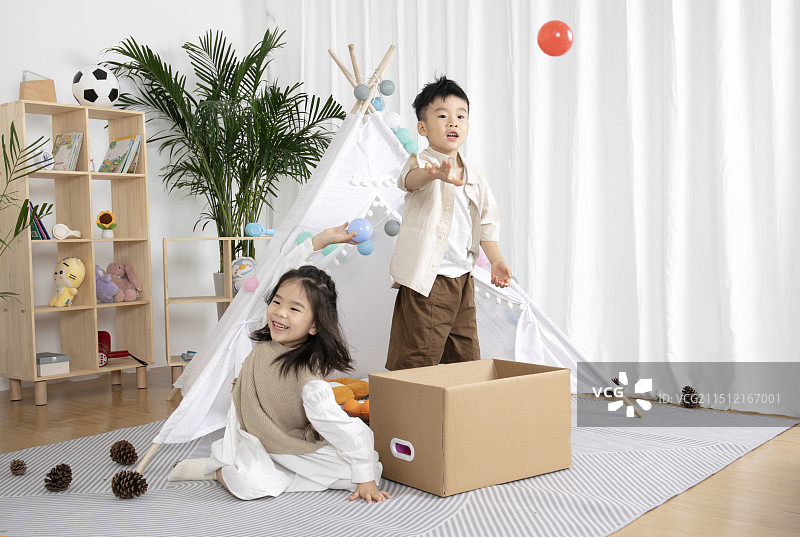 在儿童帐篷前玩纸箱子游戏的两个小朋友图片素材