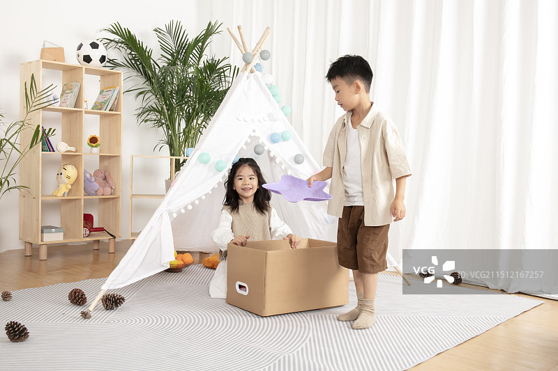 在儿童帐篷前玩纸箱子游戏的两个小朋友图片素材