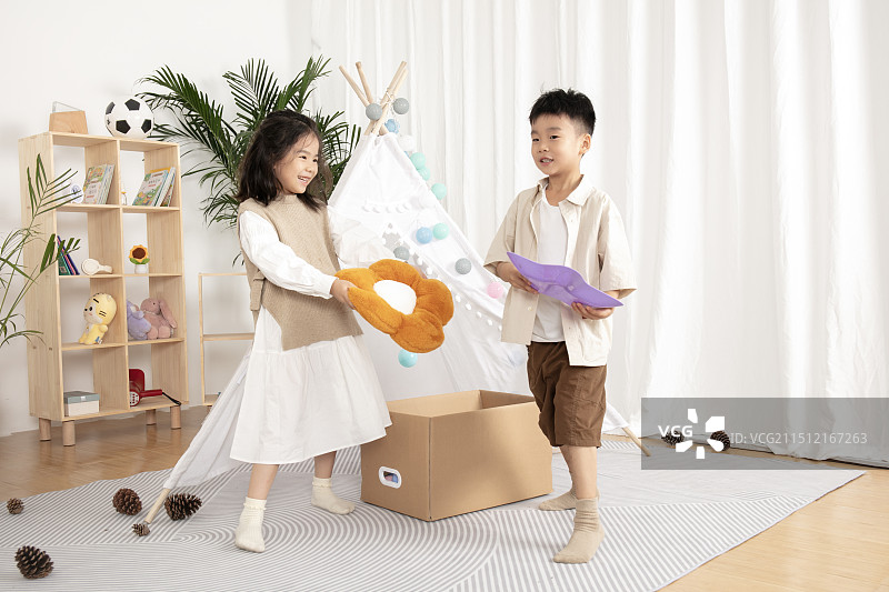 在儿童帐篷前玩纸箱子游戏的两个小朋友图片素材