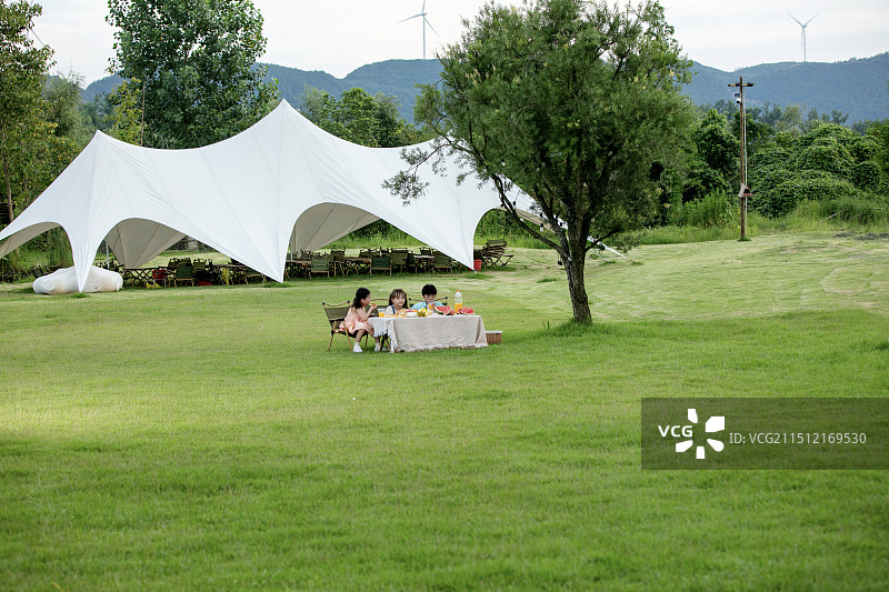 坐在户外天幕前吃水果的三个小朋友图片素材