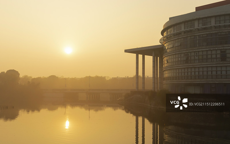晨雾中升旗的太阳与圆柱形建筑图片素材