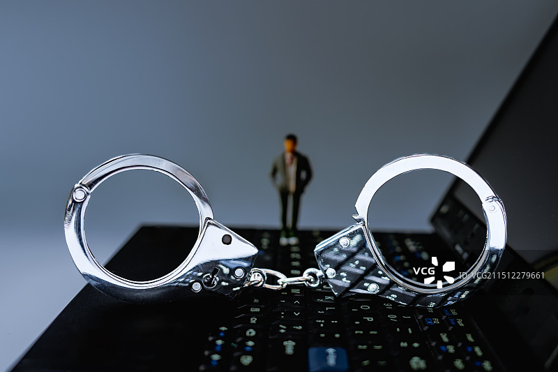 冰冷的手铐、人物与笔记本电脑图片素材