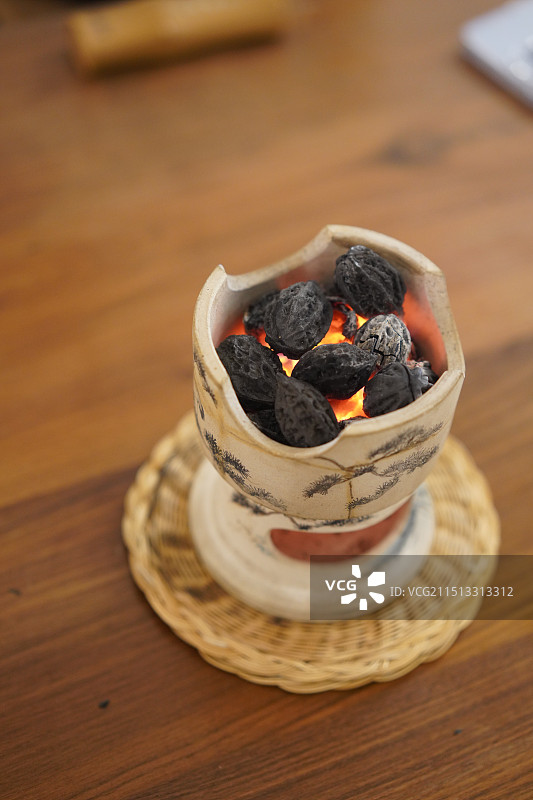 桌上手绘白泥炭炉中点燃的橄榄核碳的特写镜头图片素材