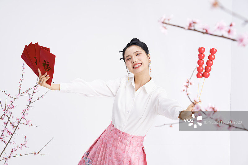 手拿红包与糖葫芦的年轻中国女人图片素材