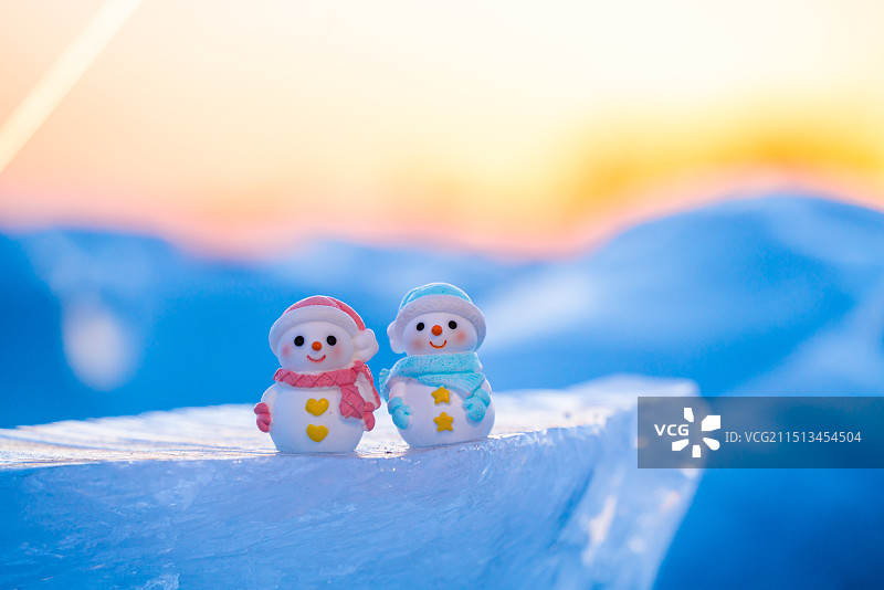 夕阳下冰块上的情侣雪人图片素材