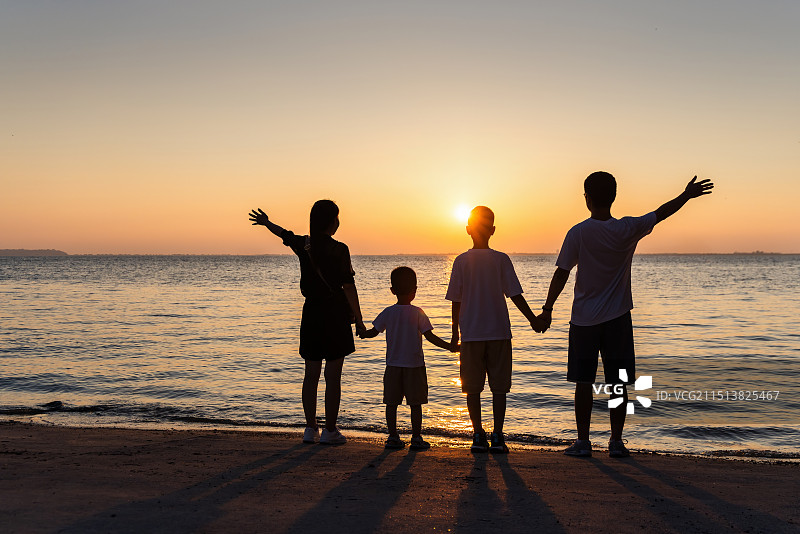 日落时海滩上的一家人牵手看日落剪影图片素材
