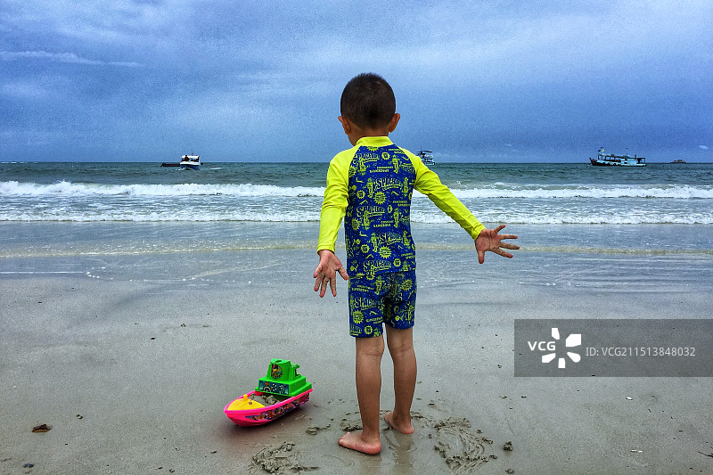 站在海滩上的男孩的后视图图片素材