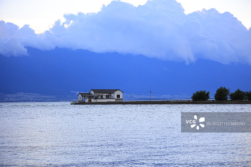 洱海湖中心独立小屋在云雾缭绕的远山背景下显得静谧而孤独，展现了自然与人居的完美融合图片素材