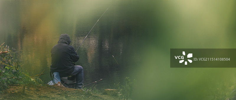 坐在河边钓鱼的人的后视图图片素材