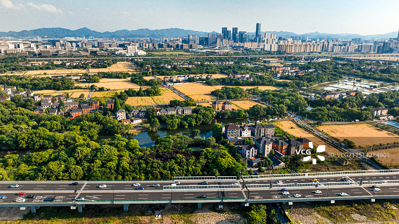 城市航拍，高架、稻田与远处的欧美金融城图片素材