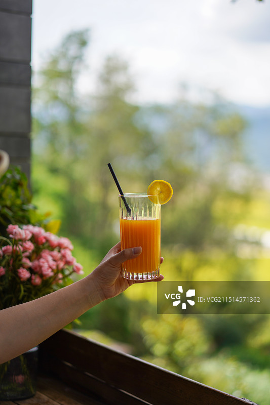 手持玻璃杯装橙汁饮料的特写镜头图片素材