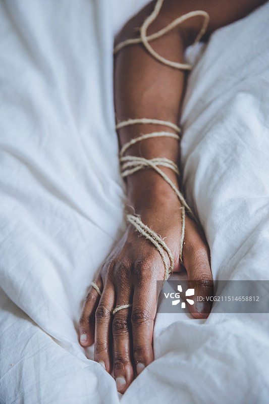 胳膊缠绕在麻线上的一个人躺在床上（腰部视角，法国勒阿弗尔）图片素材