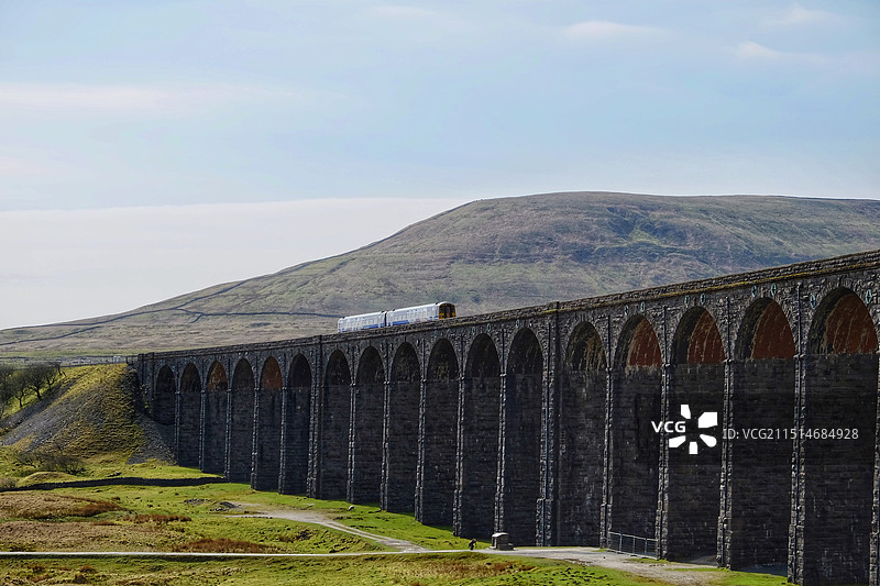 一辆火车行驶在约克郡谷地Yorkshire Dales国家公园的高架铁路桥上图片素材