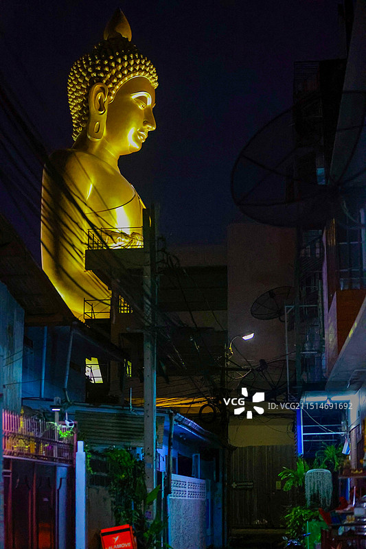 巨大的佛像闪着金光，俯视着城市中的街道，形鲜明的对比图片素材