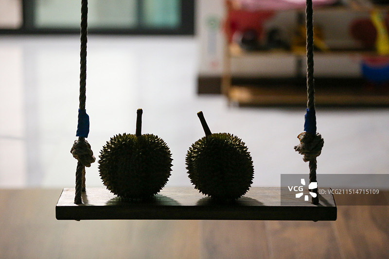 两个榴莲并排放在秋千上的剪影，形成了一种奇特的静物构图效果图片素材