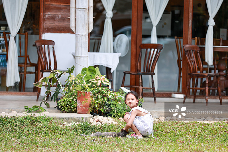 一个小女孩在庭院中撸猫图片素材