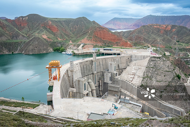 青海海南坎布拉森林公园李家峡水库大坝，高峡平湖，红色的丹霞地貌岩石加上翠绿色的树林和蓝色的天空图片素材