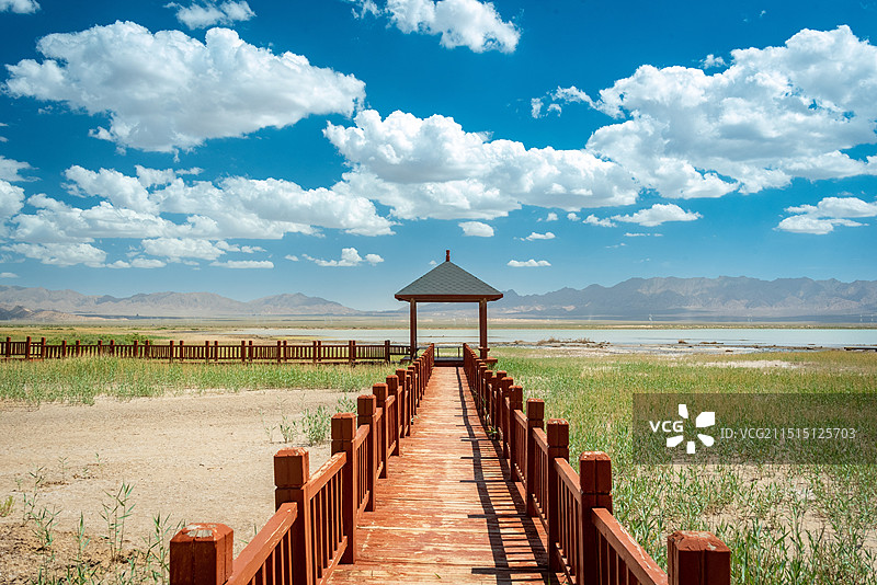 蓝天白云下德令哈尕海湿地公园平静的湖面倒影，木制亭子，木栈道向远处延伸图片素材