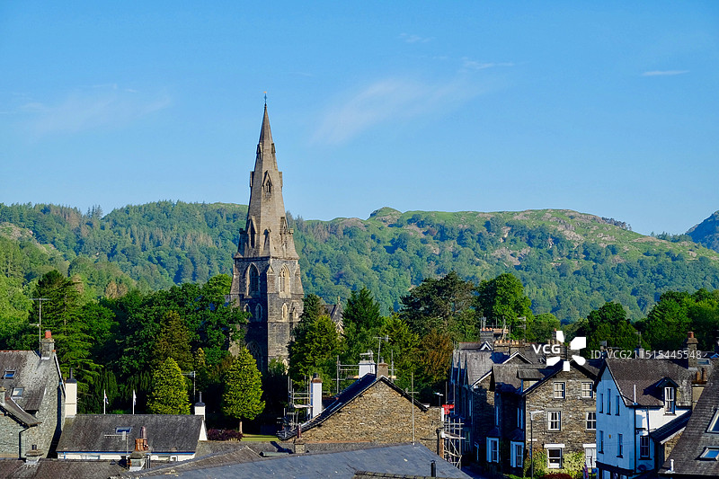 英国湖区Lake District Ambleside小镇蓝天映衬下的教堂尖顶与住宅楼景观图片素材