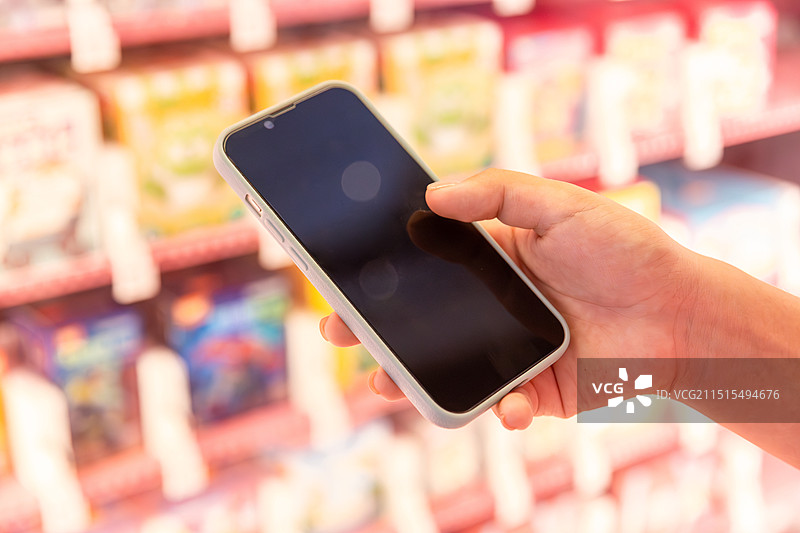 手拿着手机在自动售卖机前购买东西特写图片素材