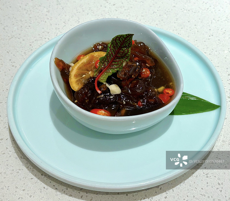 浅色桌面上餐具里的凉拌海蜇高视角俯拍图片素材