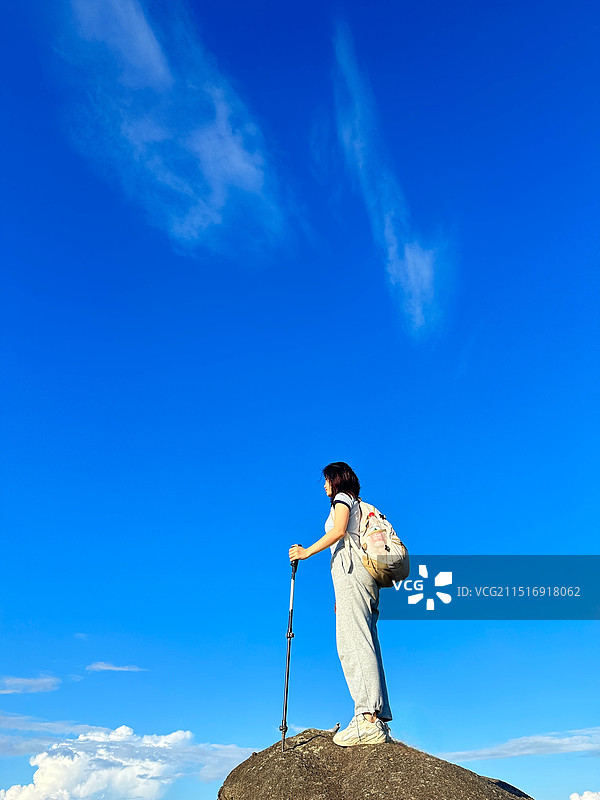 蓝天下站在岩石上的人的低角度视图图片素材