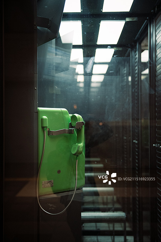 夜晚日本城市街道上的绿色公共电话的特写图片素材