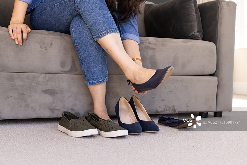 女人在客厅沙发上试穿不同的鞋子图片素材