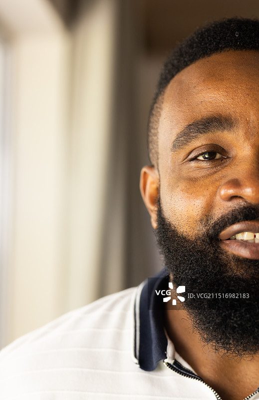 微笑的非裔美国男人，留着胡须，穿着白衬衫，室内特写图片素材