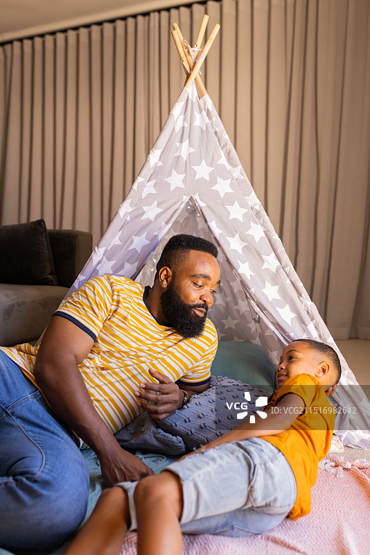 在帐篷里玩耍，父子在客厅里互动微笑，设有空白区域，在圆锥形帐篷里图片素材