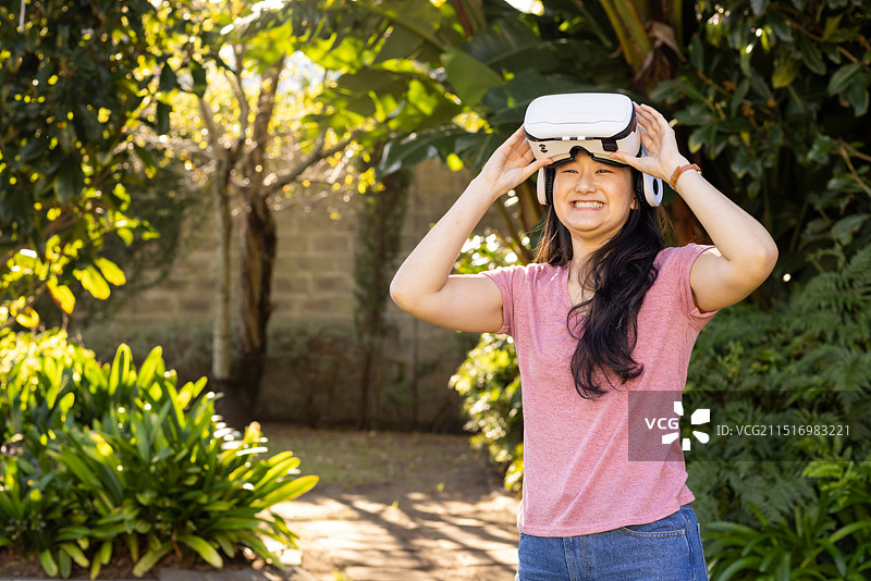 在花园里调整VR眼镜的亚洲女性图片素材