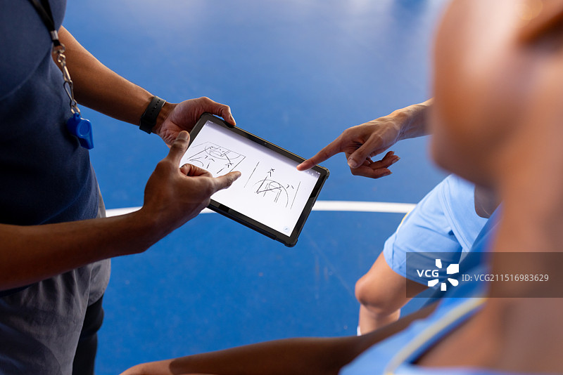 篮球教练用平板电脑与球员讨论比赛策略图片素材