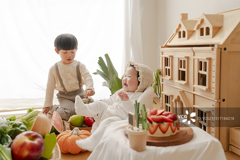 丰盛的果蔬堆中可爱的小哥哥与快乐的女婴妹妹图片素材