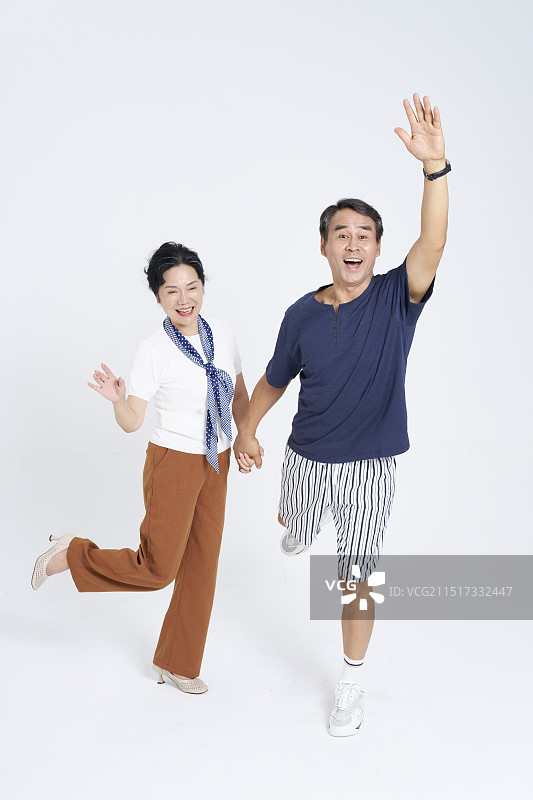 手牵手朝远方打招呼的两个老年人图片素材