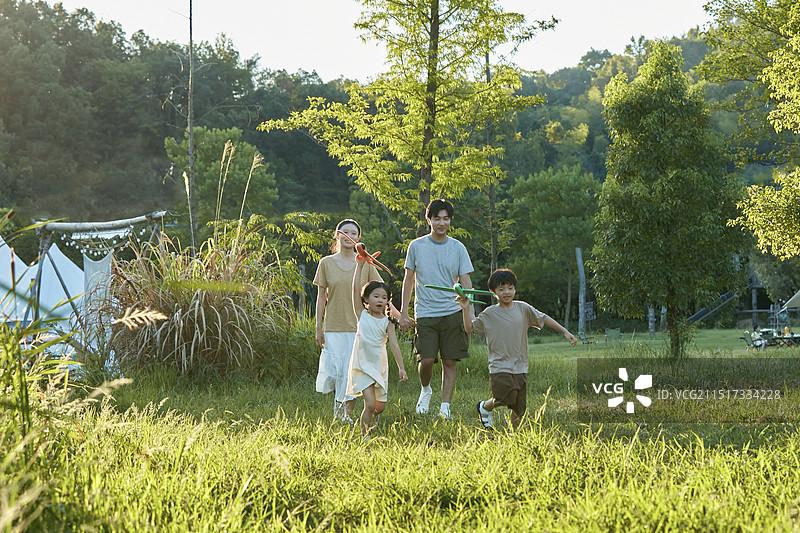 夕阳下手拿飞机模型飞奔的一家四口图片素材