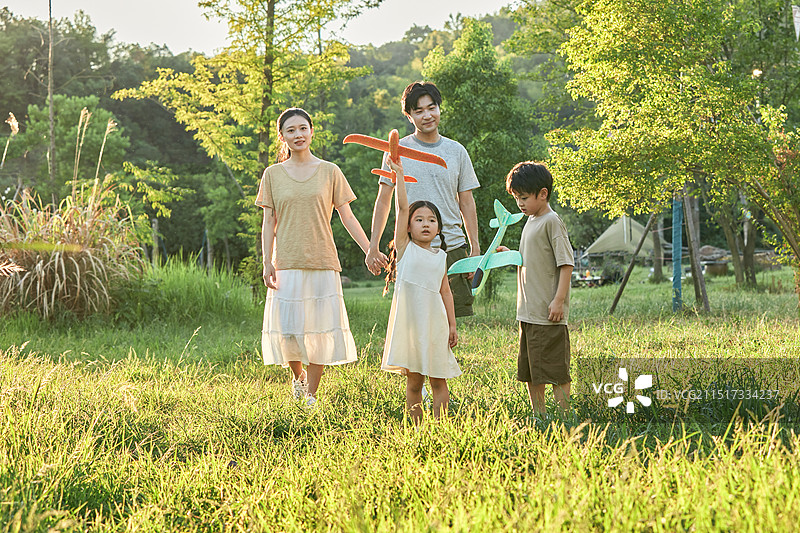 夕阳下手拿飞机模型飞奔的一家四口图片素材