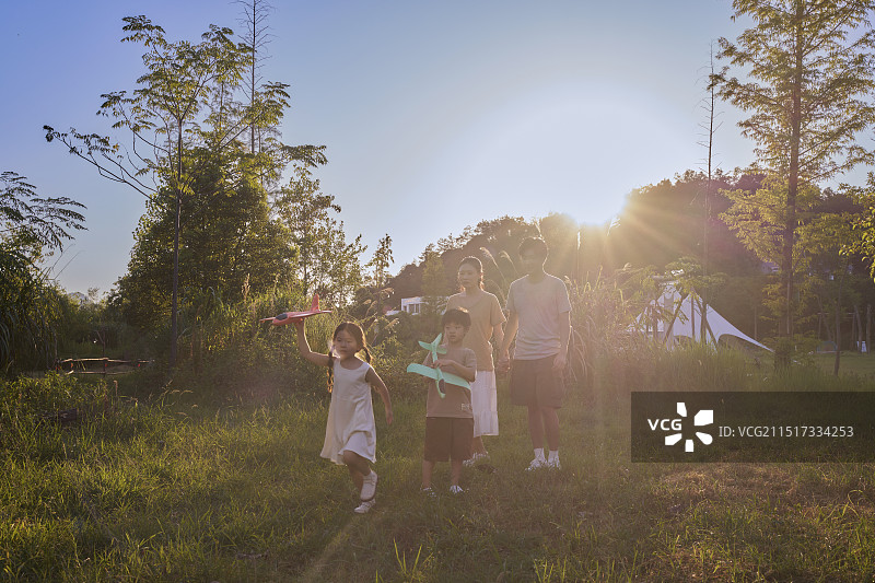 夕阳下手拿飞机模型飞奔的一家四口图片素材