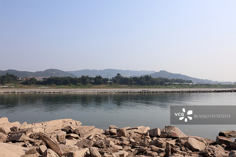 蓝天映衬下的长江流域静静的水面和江岸的石块图片素材