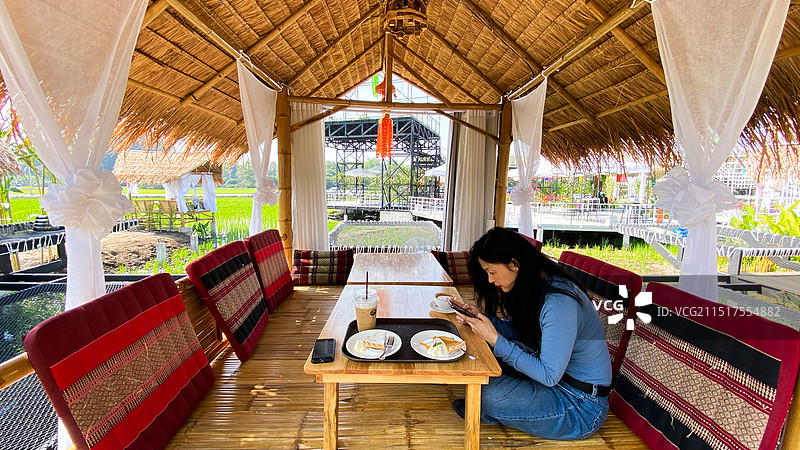 一个女人坐在台式餐厅茅草房中用餐图片素材